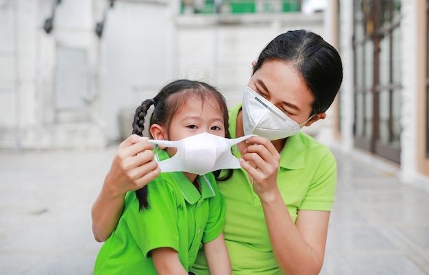 Jeune maman portant un masque de protection pour sa fille à l&#39;extérieur contre la pollution de l&#39;air dans la ville de Bangkok