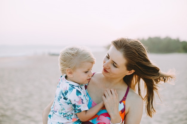 Jeune maman porte sa fille sur la plage