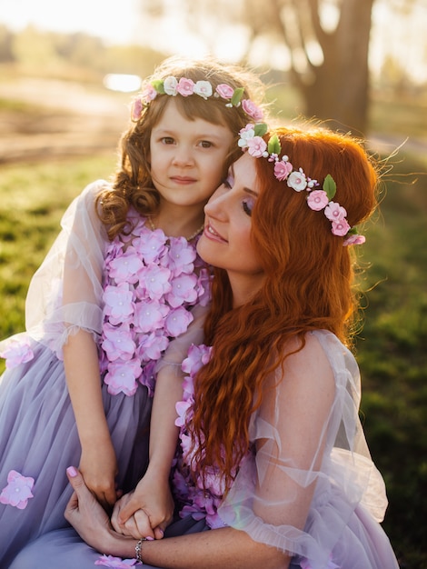 Jeune maman rousse avec sa fille reposant sur la nature au soleil