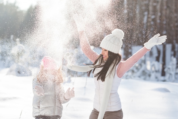 Jeune maman et sa fille s'amusant dans la neige