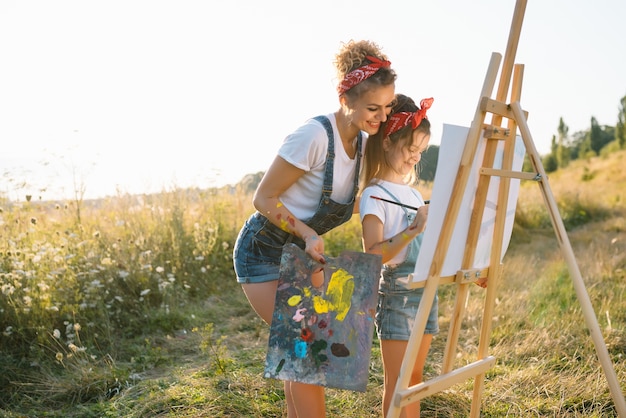 Jeune maman et sa fille s'amusent,. mère souriante avec belle fille dessine la nature