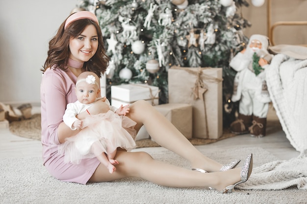 Jeune maman et sa petite fille avec arbre de Noël