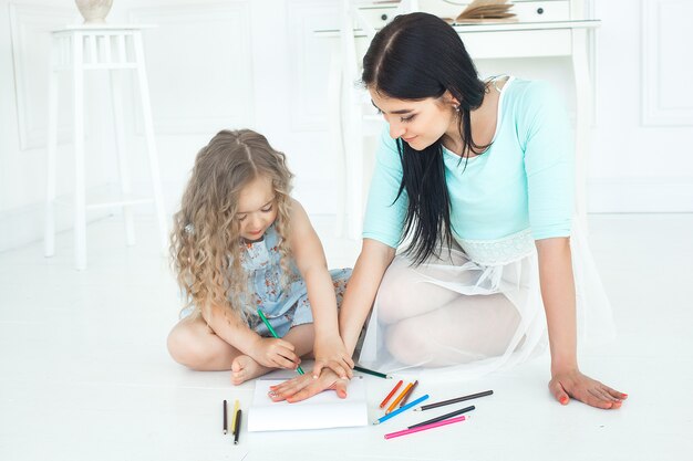 Jeune maman et sa petite fille jouant ensemble. Famille drowing avec des crayons colorés