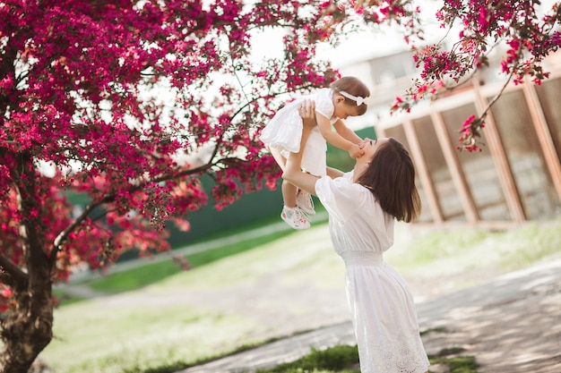 Jeune Maman Et Sa Petite Fille Marchant Ensemble Dans Le Parc Au Printemps. Famille Heureuse à L'extérieur. Aimer Avec Une Adorable Petite Fille.