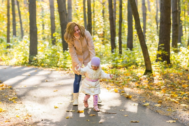 Jeune maman et sa petite fille s'amusent à l'automne