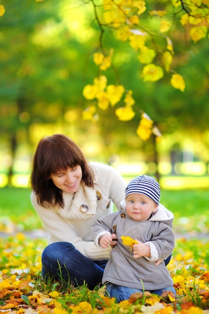 Jeune maman avec son petit bébé s&#39;amuser dans le parc en automne