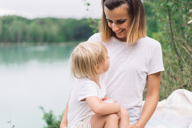 Jeune maman tenant son bébé. Mère et petite fille s'amusant dans la nature.