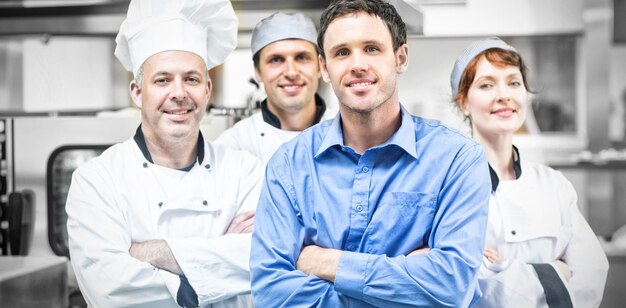 Jeune manager posant avec des chefs dans une cuisine