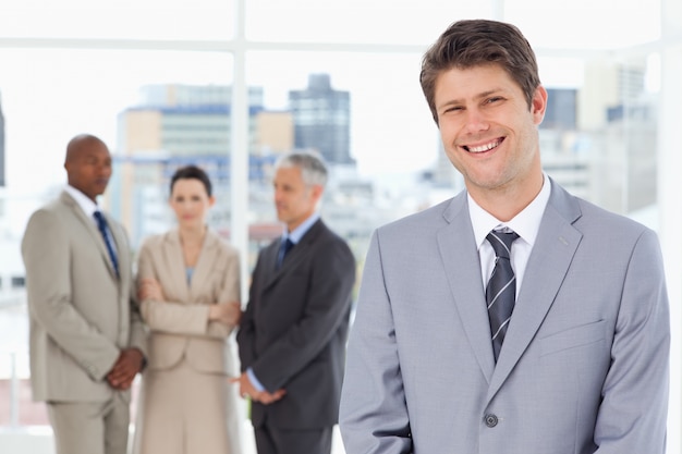 Jeune manager souriant debout avec son équipe derrière lui