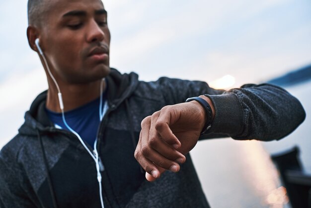 Un jeune mannequin africain regarde sa smartwatch pour suivre la distance parcourue