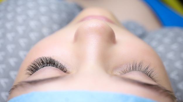 Photo un jeune mannequin est allongé sur un canapé de cosmétologie avec des cils étendus sur un œil le résultat est avant après les yeux gauche et droit