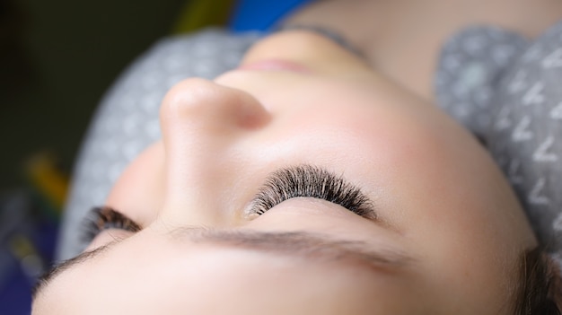 Un jeune mannequin est allongé sur le canapé, le résultat final du travail est une extension de cils en gros plan