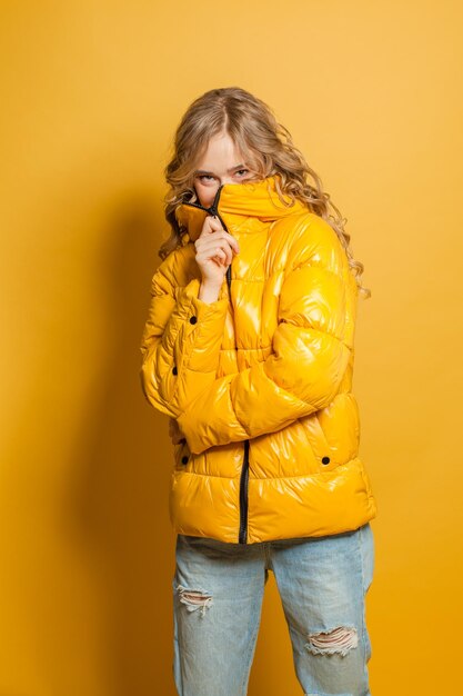 Photo jeune mannequin de mode assez joyeuse femme en veste d'hiver sur fond jaune vif