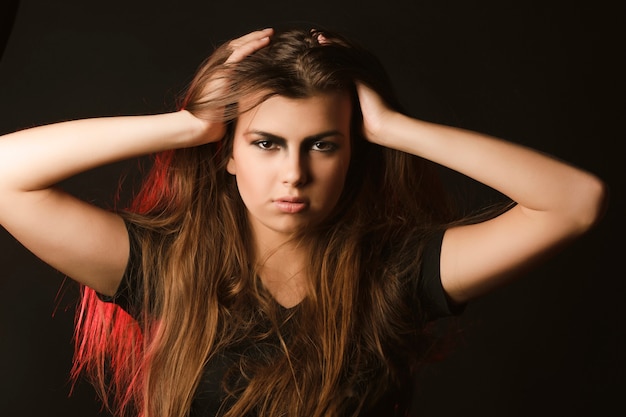 Jeune mannequin à la mode avec le maquillage d'art posant au studio avec la lumière rouge