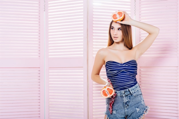 Jeune mannequin posant en maillot de bain bleu et avec des fruits sur la tête