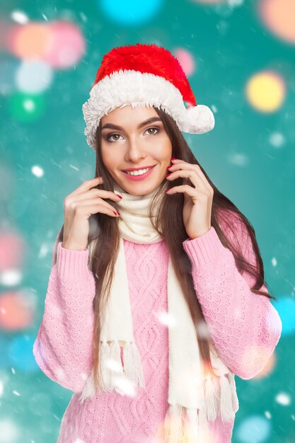 Jeune mannequin en pull rose et chapeau de père Noël en studio