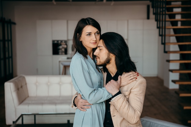 Le jeune mari embrasse doucement sa femme dans le salon. Photo de haute qualité