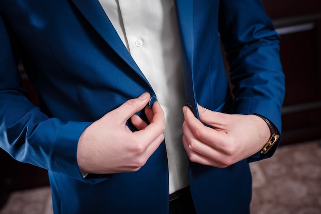 Le jeune marié le jour du mariage. il boutonne les boutons de sa veste