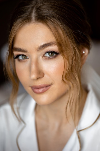 Une jeune mariée avec une chemise blanche et des yeux verts regarde dans l'appareil-photo