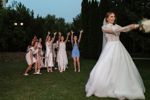 Une jeune mariée dans une robe blanche jette un bouquet de mariage