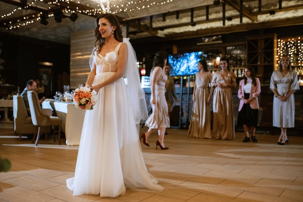 La jeune mariée dans une robe blanche jette un bouquet de mariage