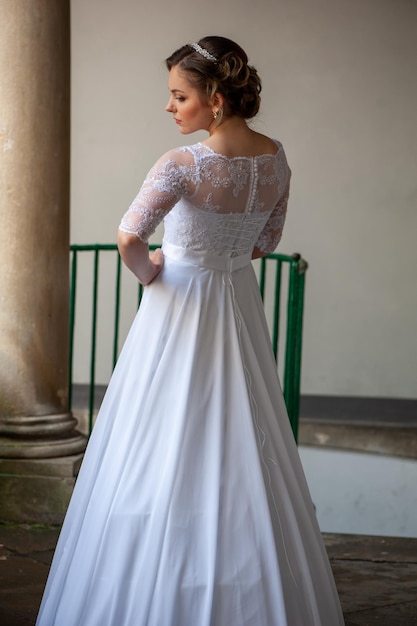 Une jeune mariée dans une robe blanche se tient dans une porte