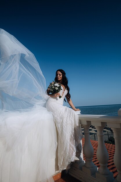 Jeune mariée luxueuse dans une garde-robe à la mode chère pose pour une séance photo de mariage dans une station balnéaire de luxe