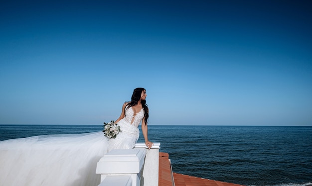 Jeune mariée luxueuse dans une garde-robe à la mode chère pose pour une séance photo de mariage dans une station balnéaire de luxe