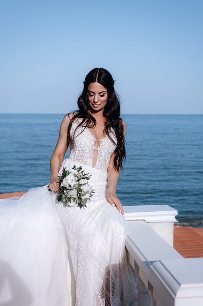 Jeune mariée luxueuse dans une garde-robe à la mode chère pose pour une séance photo de mariage dans une station balnéaire de luxe