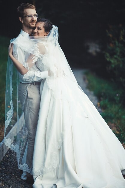 Une jeune mariée et le marié debout ensemble en plein air, l'heure d'été