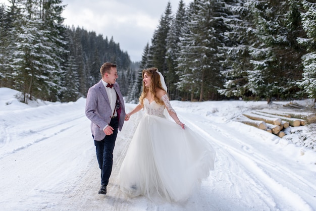 Jeune mariée et le marié sur la forêt enneigée