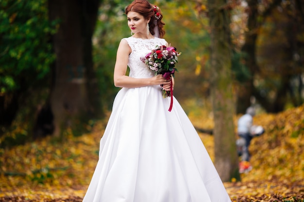 Jeune mariée en robe de mariée marchant dans un parc. Mode robe de luxe blanche pour femme. La mariée se promène dans le parc.