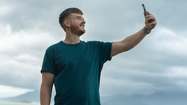 Jeune mec bel homme heureux en mer prend une photo de lui-même selfie à la caméra de son téléphone en utilisant