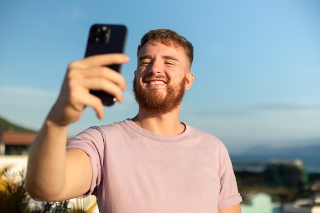 Photo jeune mec bel homme heureux prend une photo de lui-même selfie à la caméra de son téléphone en utilisant