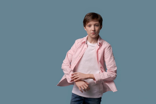 Jeune mec en chemise rose et t-shirt blanc pose en studio sur fond bleu