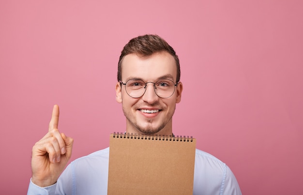 Un jeune mec cool dans une chemise doucement bleue avec des lunettes apparaît