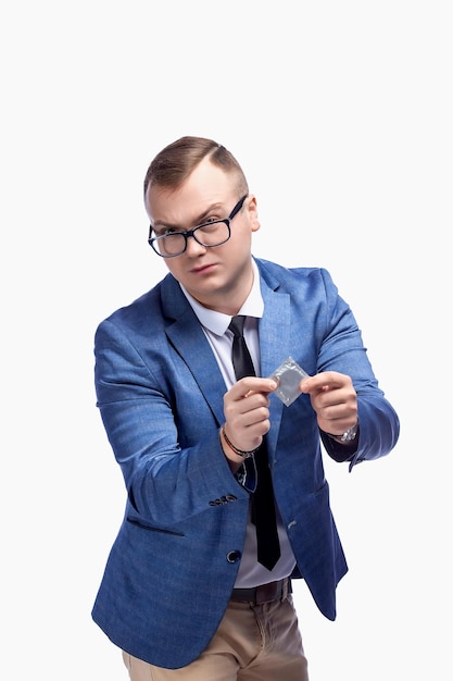 Jeune mec dans une veste noeud papillon lunettes tient un préservatif dans sa main isolé sur fond blanc