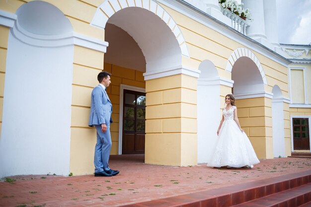 Photo jeune mec élégant dans le costume du marié et de la mariée belle fille en robe blanche avec une promenade en train dans le parc le jour de leur mariage