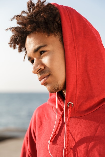 Jeune mec à l'extérieur sur la plage, écouter de la musique avec des écouteurs