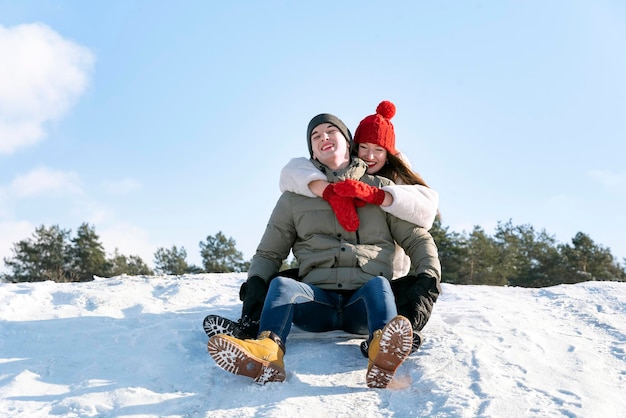 Jeune mec et une fille glissent sur le toboggan de neige Journée ensoleillée d'hiver Couple à l'extérieur