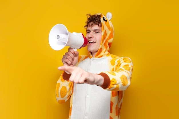 Jeune mec joyeux en pyjama girafe drôle pour enfants parle dans un mégaphone