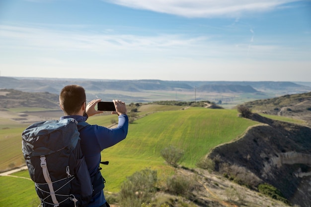 Jeune mec méconnaissable avec un sac à dos prenant une photo avec son portable