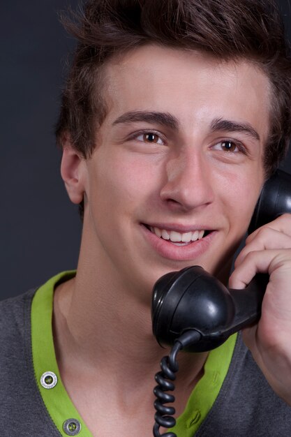 Jeune mec parlant au vieux téléphone et souriant