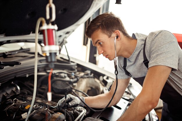 Un jeune mécanicien diplômé recherche des bugs au travail dans un service automobile.