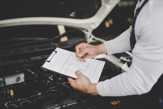 Jeune mécanicien tenant la liste de contrôle de presse-papiers de la voiture