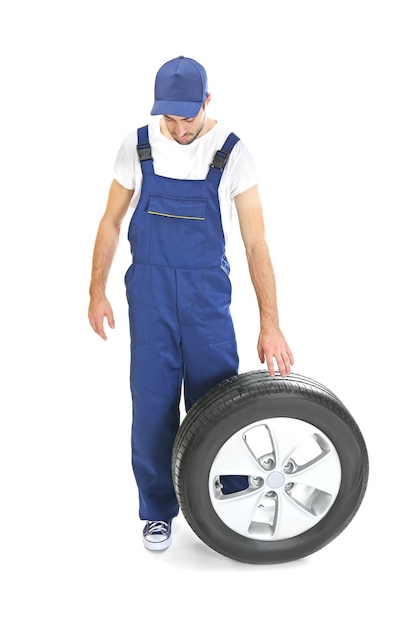 Jeune mécanicien en uniforme avec roue sur fond blanc