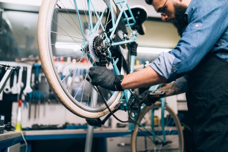 Photo jeune mécanicien vélo barbe réparant des vélos dans un atelier.