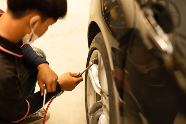 Jeune mécanicien vérifiant la pression de l&#39;air et remplissant les pneus.