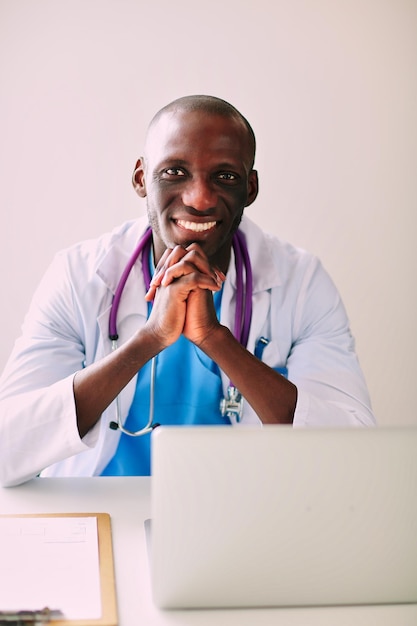 Jeune médecin africain travaillant sur ordinateur portable au bureau