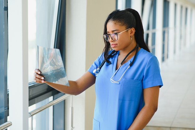 Jeune médecin afro-américain professionnel examinant la radiographie de la poitrine du patient